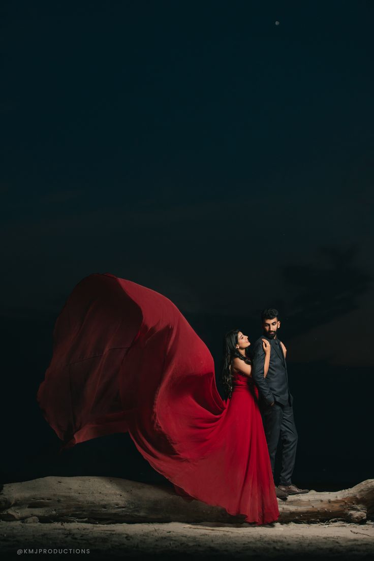 a man and woman standing on top of a tree trunk at night with the moon in the background