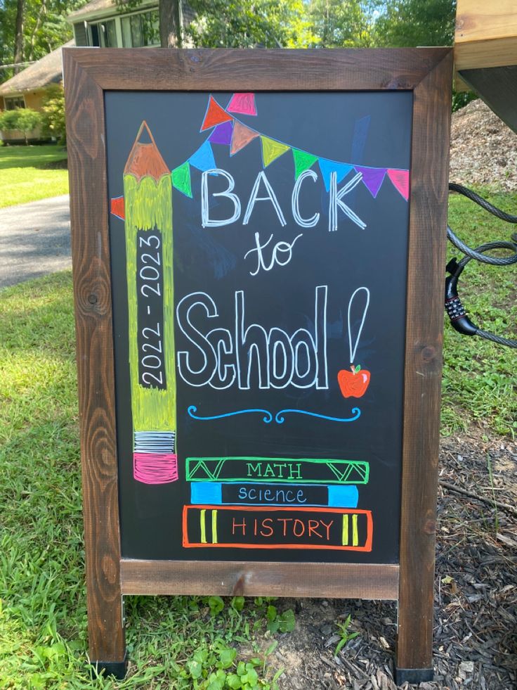 back to school chalkboard sign in front of a park with trees and grass behind it