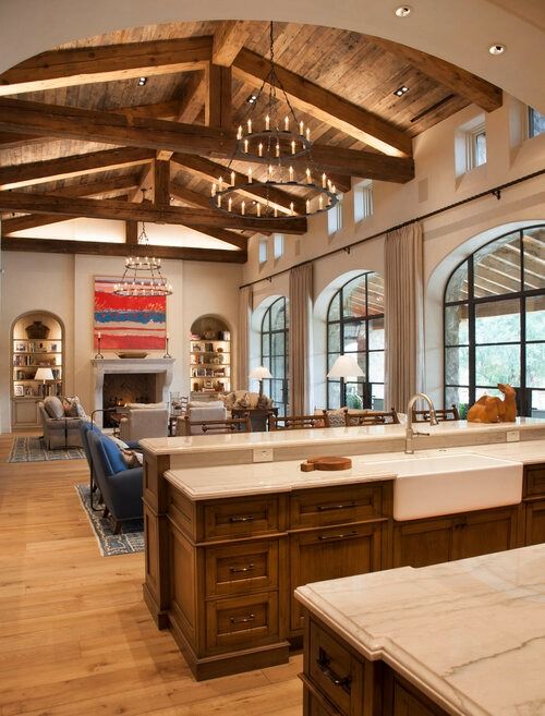 a large kitchen with wooden beams and white counter tops, along with an island in the middle