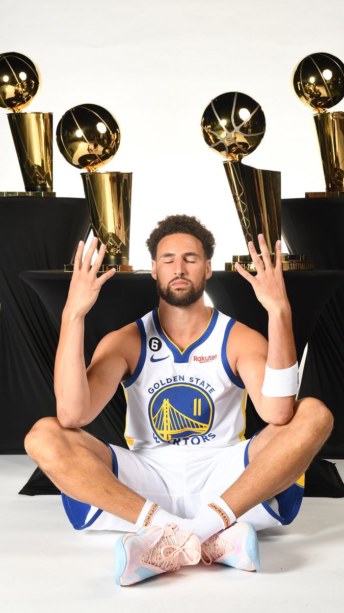 a man sitting on the floor with trophies in front of him and holding his hands up