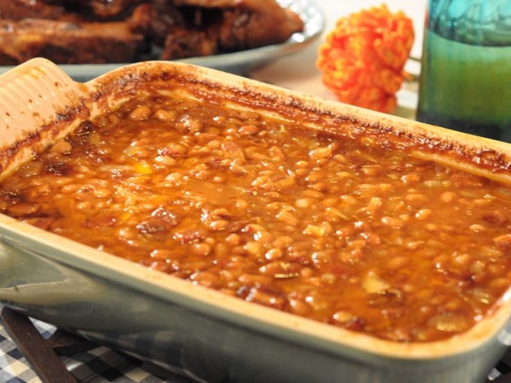 a casserole dish filled with baked beans on a table next to other dishes