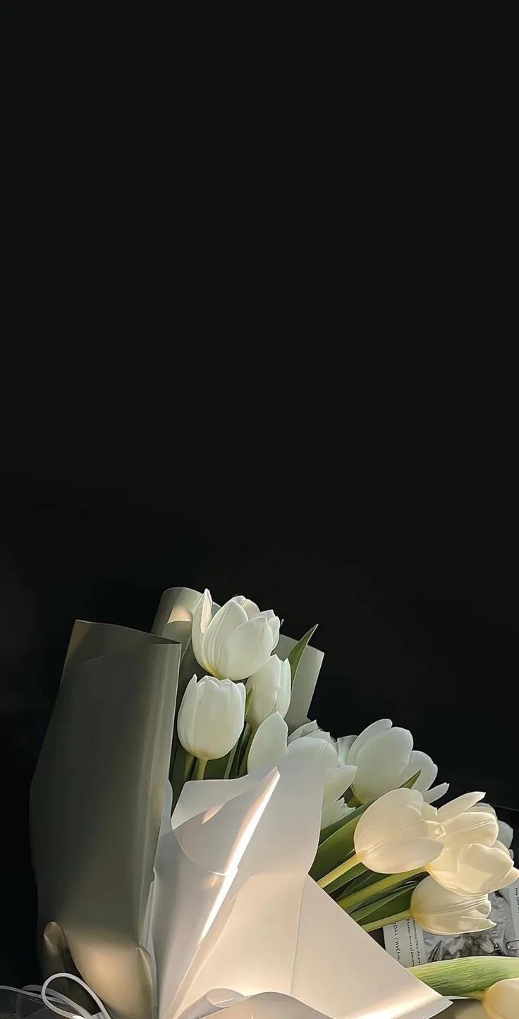 white tulips and other flowers on a black background with an envelope in the foreground