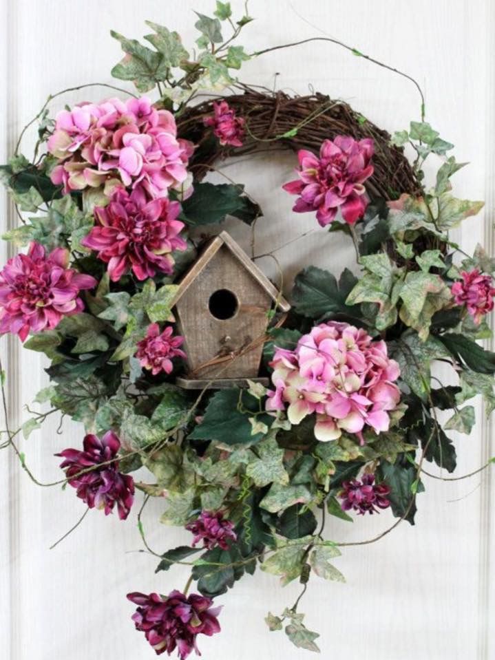 a wreath with pink flowers and a birdhouse