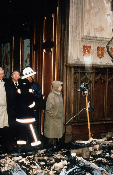 several people standing in front of a fire damaged building