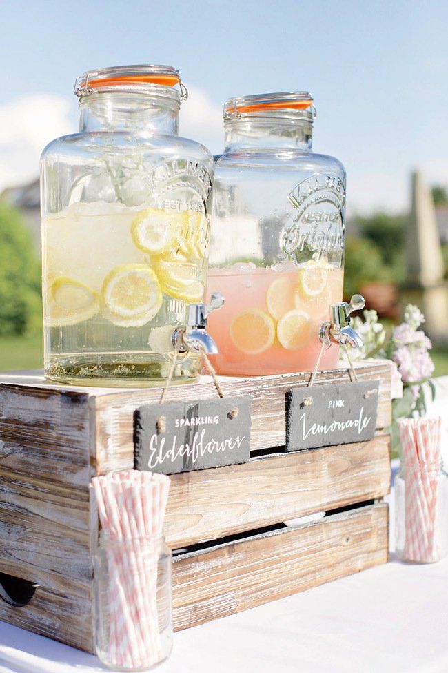 two mason jars filled with lemonade sit on top of a wooden crate at an outdoor wedding