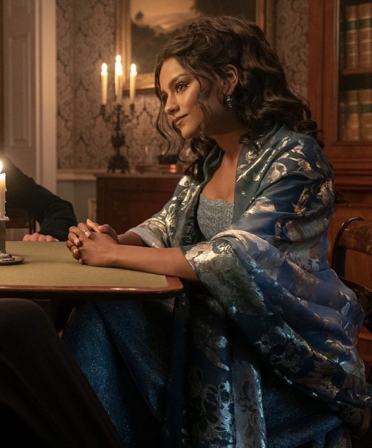 a woman sitting at a table with a candle in her hand