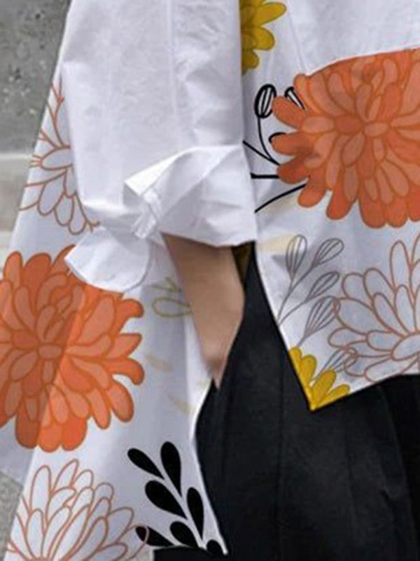 the back of a woman's white shirt with orange flowers and leaves on it