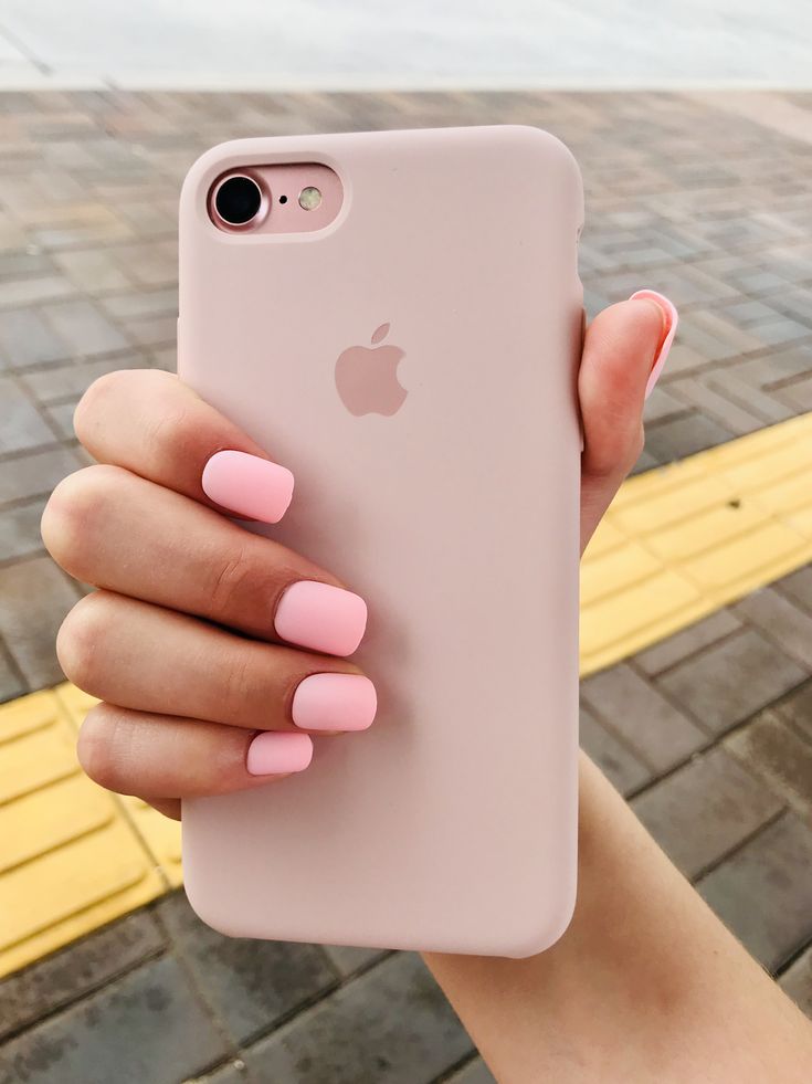 a woman holding up an iphone case with pink nail polish on her nails and one hand