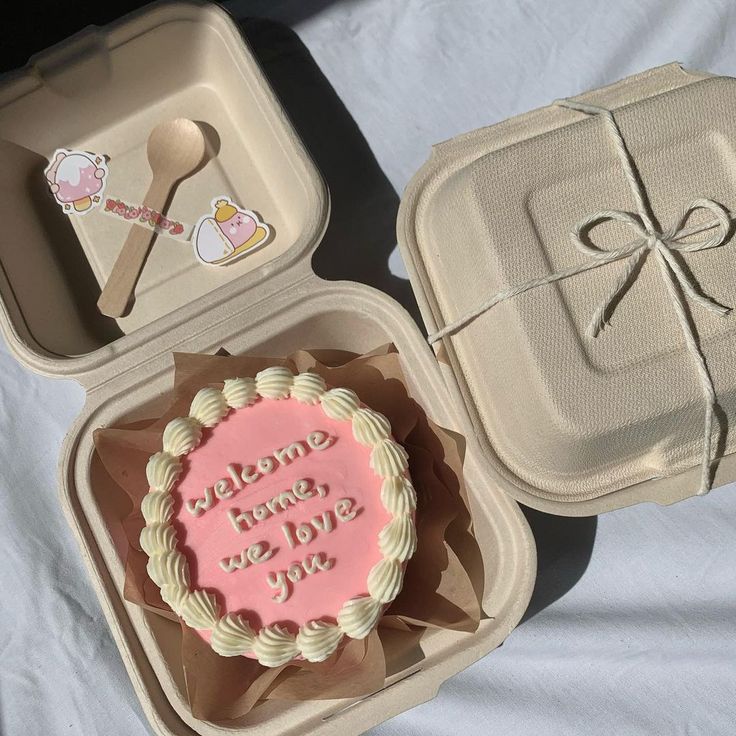 there is a cake in a box and a cupcake on the table next to it