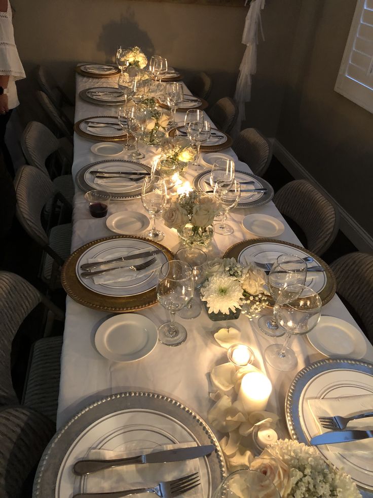 a long table is set with white plates and silverware for dinner guests to enjoy