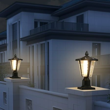 two lamps on the side of a building in front of a white fence and windows