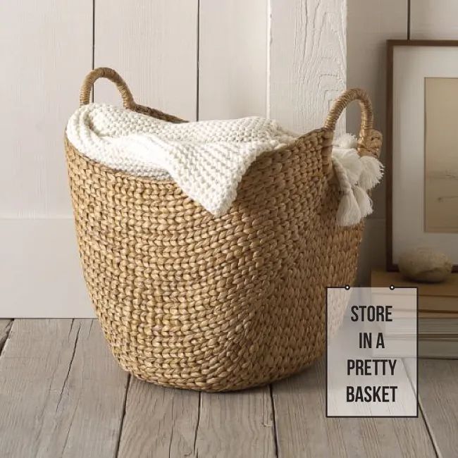 a large woven basket sitting on top of a wooden floor next to a framed photo