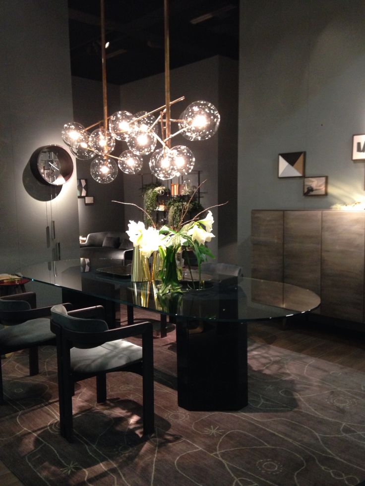 a dining room table with chairs and lights hanging from it's ceiling over it