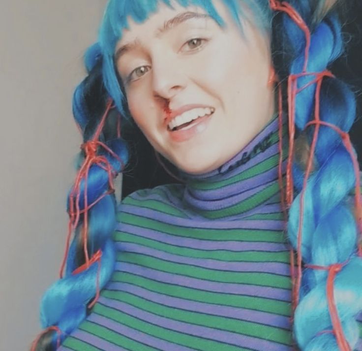 a woman with blue and green hair is smiling