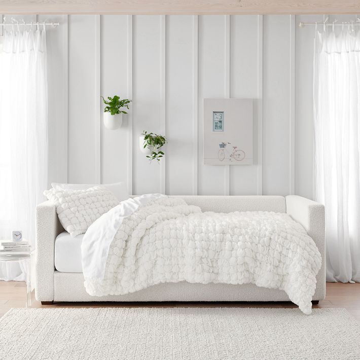 a white bed sitting on top of a wooden floor