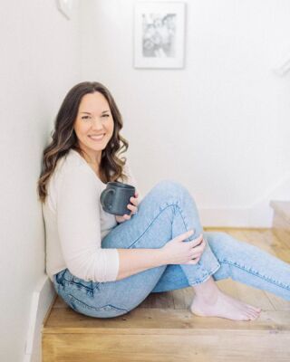 a woman sitting on the floor holding a cup