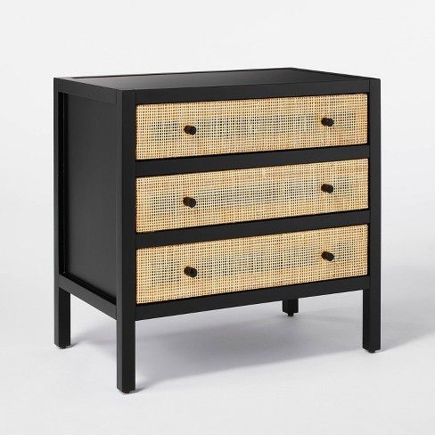 a black and rattan dresser with three drawers on one side, two wicker drawers on the other