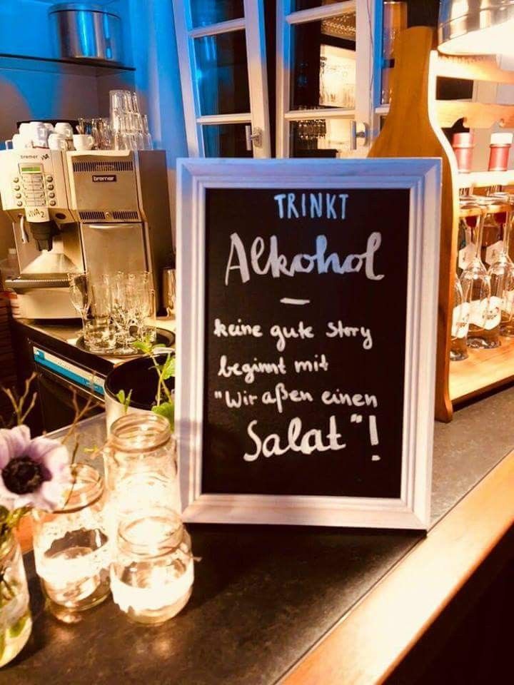 a chalkboard sign sitting on top of a counter next to jars filled with water