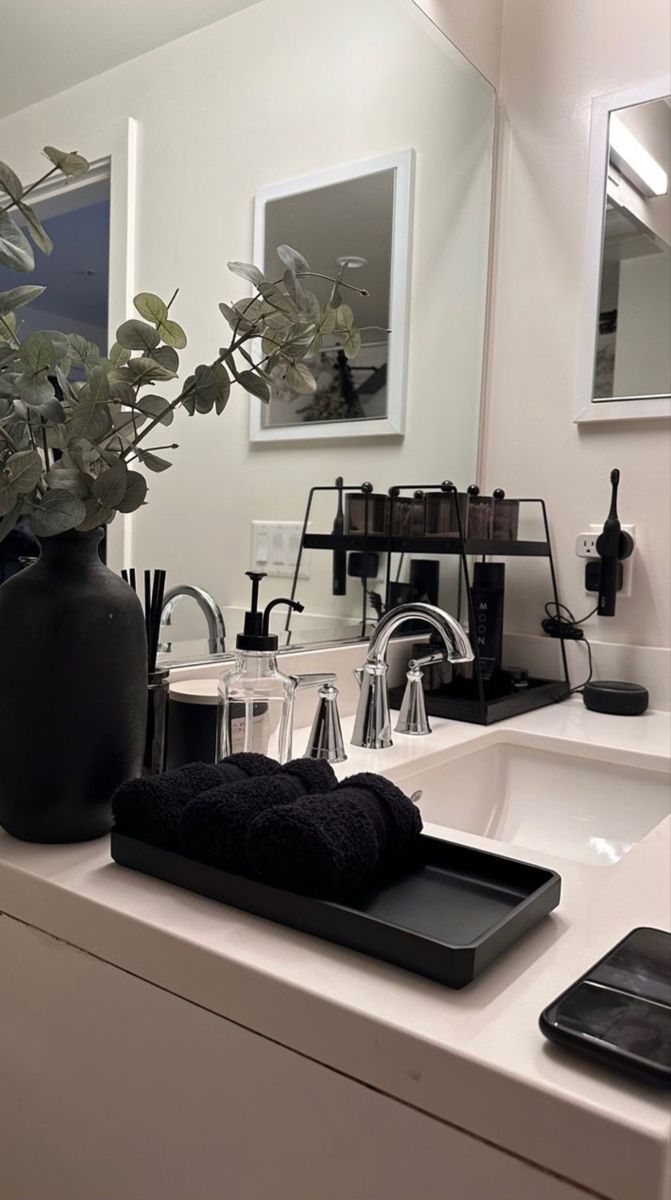 a bathroom with a sink, mirror and plants in the vase on the counter top