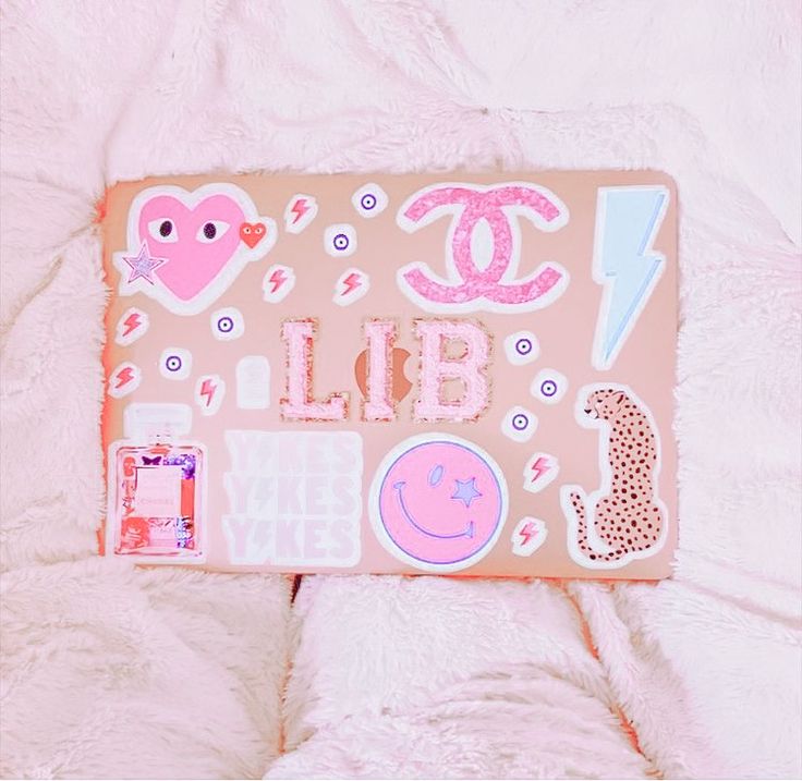 a pink bag with stickers on it sitting on a white bed next to a stuffed animal