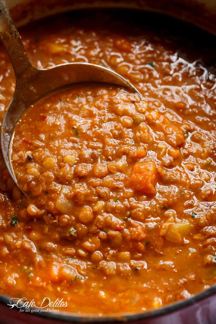 a ladle scooping up some food out of a pot filled with beans and carrots