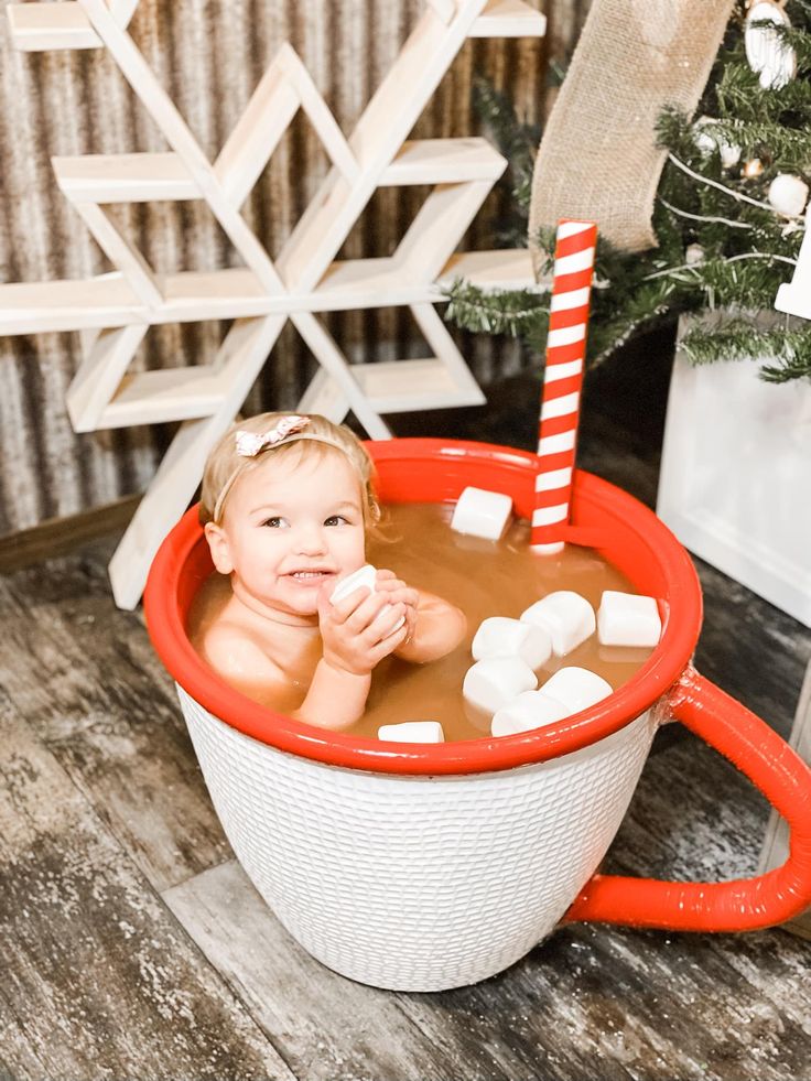 a small child in a hot tub with marshmallows on the side and a candy cane sticking out of it