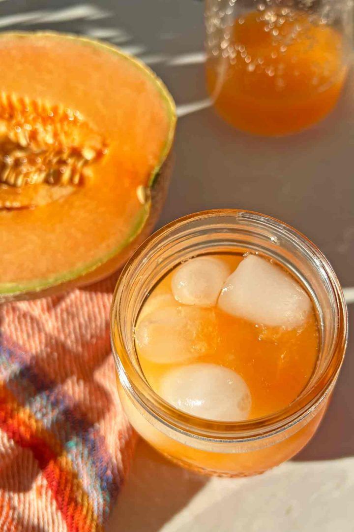 a jar filled with ice next to a cantaloupe