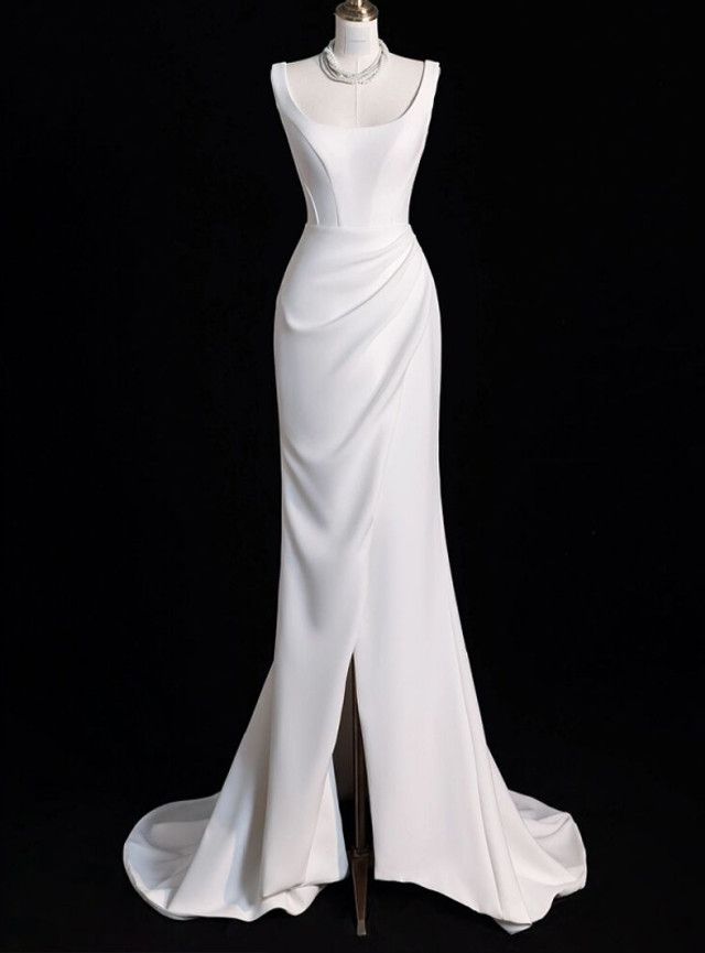 a white wedding dress on display in front of a black background with a mannequin