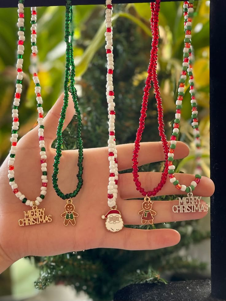 a person's hand holding several different necklaces