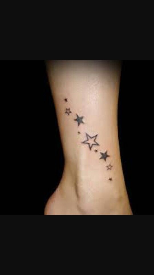 a small star tattoo on the side of a woman's foot, with stars all over it