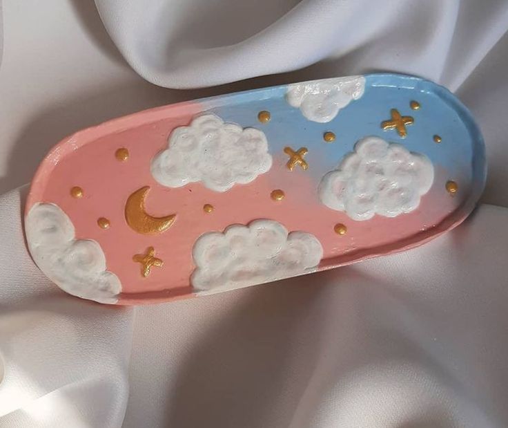 a pink, blue and white object with clouds and stars in the sky on it