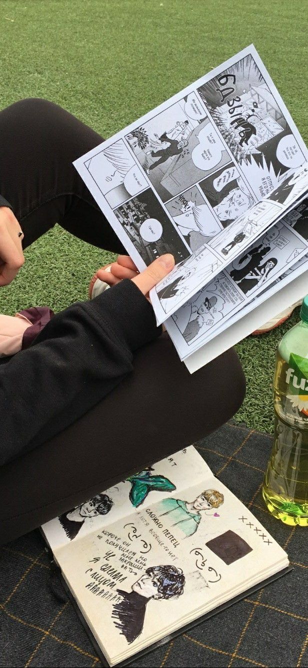 a woman sitting on the ground reading a comic book