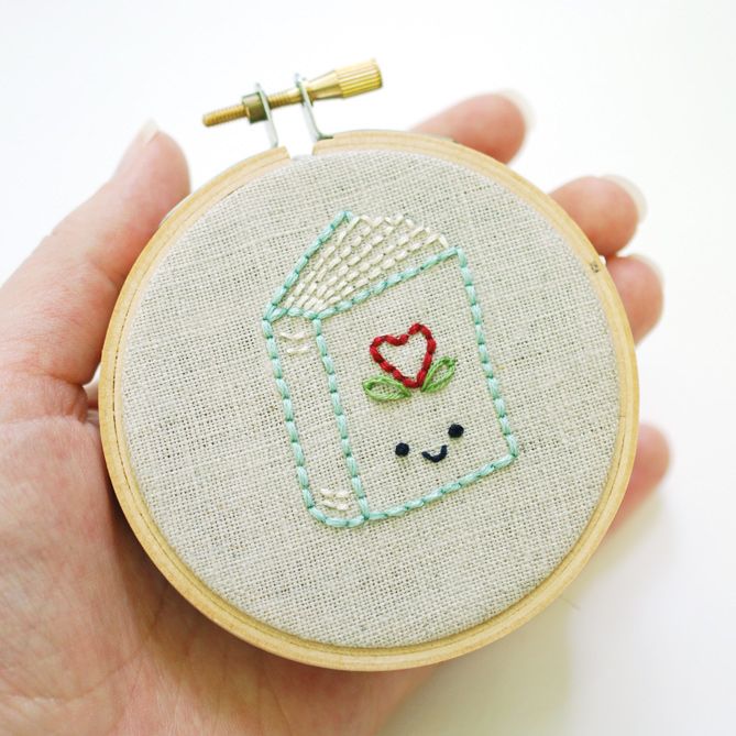 someone is holding up a small embroidery project with a jar on it's face