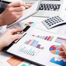 two people working at a table with papers and calculators on top of it