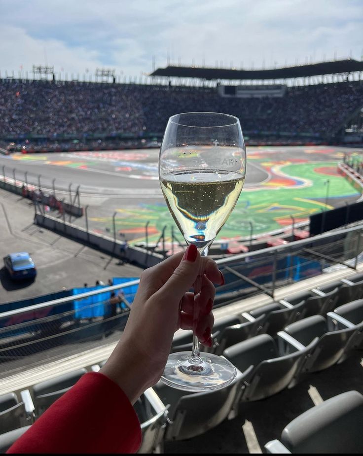 a person holding a wine glass in front of an empty stadium