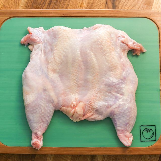 a raw chicken on a green cutting board