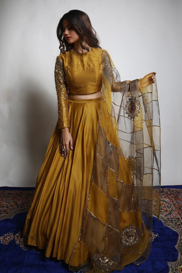 Burnt gold and grey dupion silk lehenga with heavily embroidered sleeves. Comes with a padded blouse and an organza dupatta having dual coloured patchwork, including zari and sequins hand embroidered chakra motifs .
Component: 3
Pattern: Embroidered
Type Of Work: Zari, Sequins
Neckline: V Neck
Sleeve Type: Three quarter
Fabric: Lehenga and Blouse: Dupion Silk, Dupatta : Organza 
Color: Gold
Other Details: 
Closure : Blouse : Back with Hook and Eye, Lehenga : Opening on the side with Zip and Hook Long Sleeve Lehenga, Lehenga With Long Choli, Hand Work Lehenga, Zari Lehenga, डिजाइनर कपड़े, Lehenga And Blouse, Long Blouse Designs, Gold Lehenga, Simple Lehenga