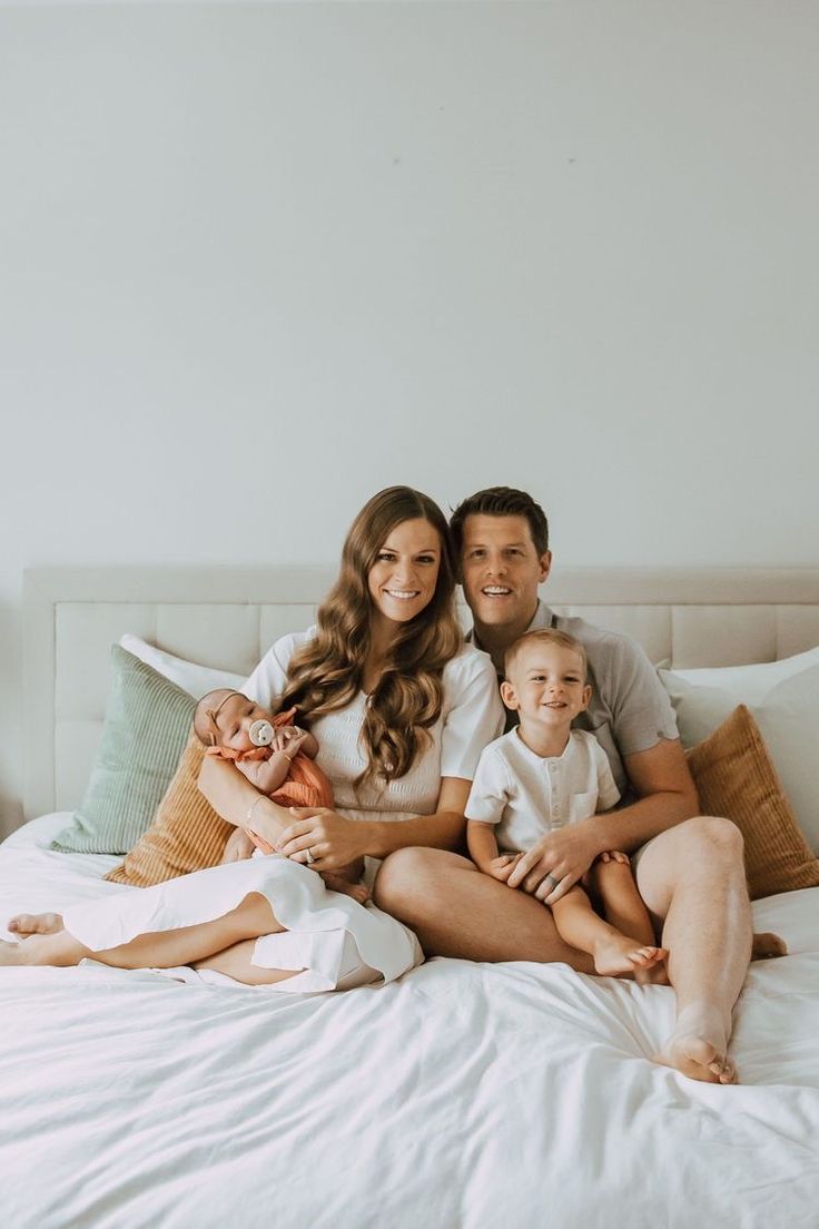 a man, woman and baby sitting on a bed together