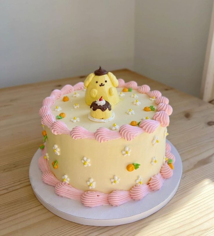 a yellow and pink birthday cake with a small dog on it's icing