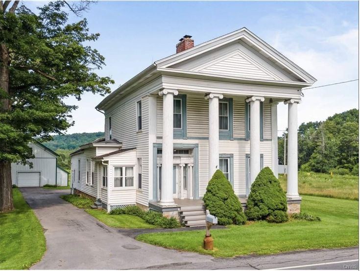 a large white house sitting on top of a lush green field