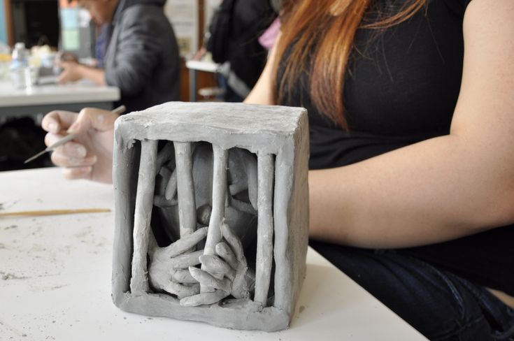 a woman sitting at a table working on a sculpture