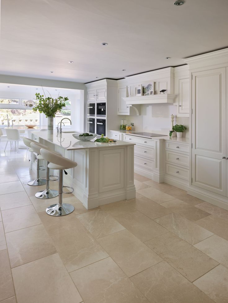 a large kitchen with white cabinets and marble flooring