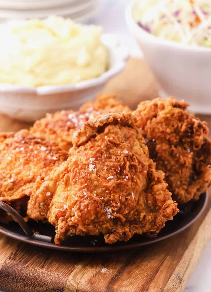 fried chicken on a plate with coleslaw and mashed potatoes in the background