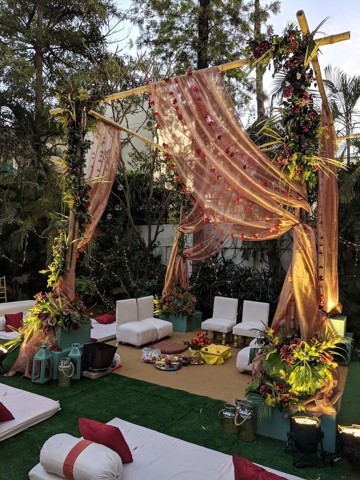 an outdoor ceremony setup with white couches and pink draping on the grass