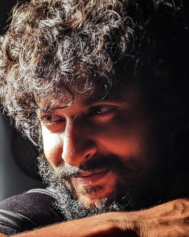 a close up of a person with curly hair and a beard looking at his cell phone