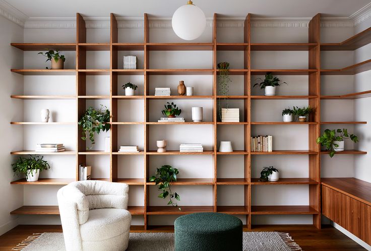 a living room filled with lots of wooden shelves and plants on top of bookshelves