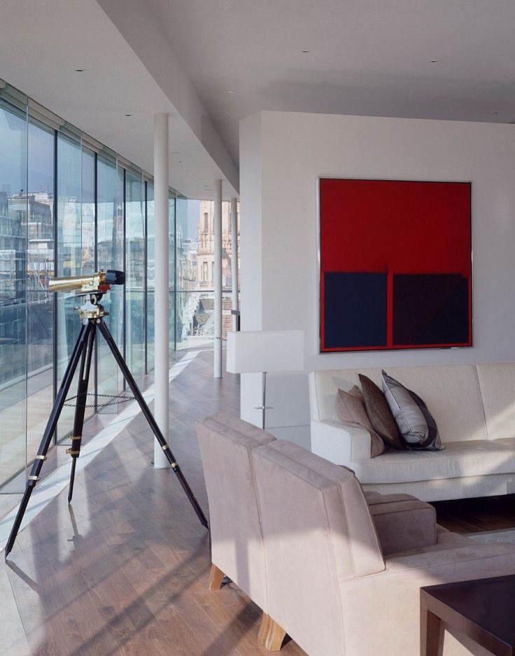 a living room filled with furniture next to tall windows and a large painting on the wall