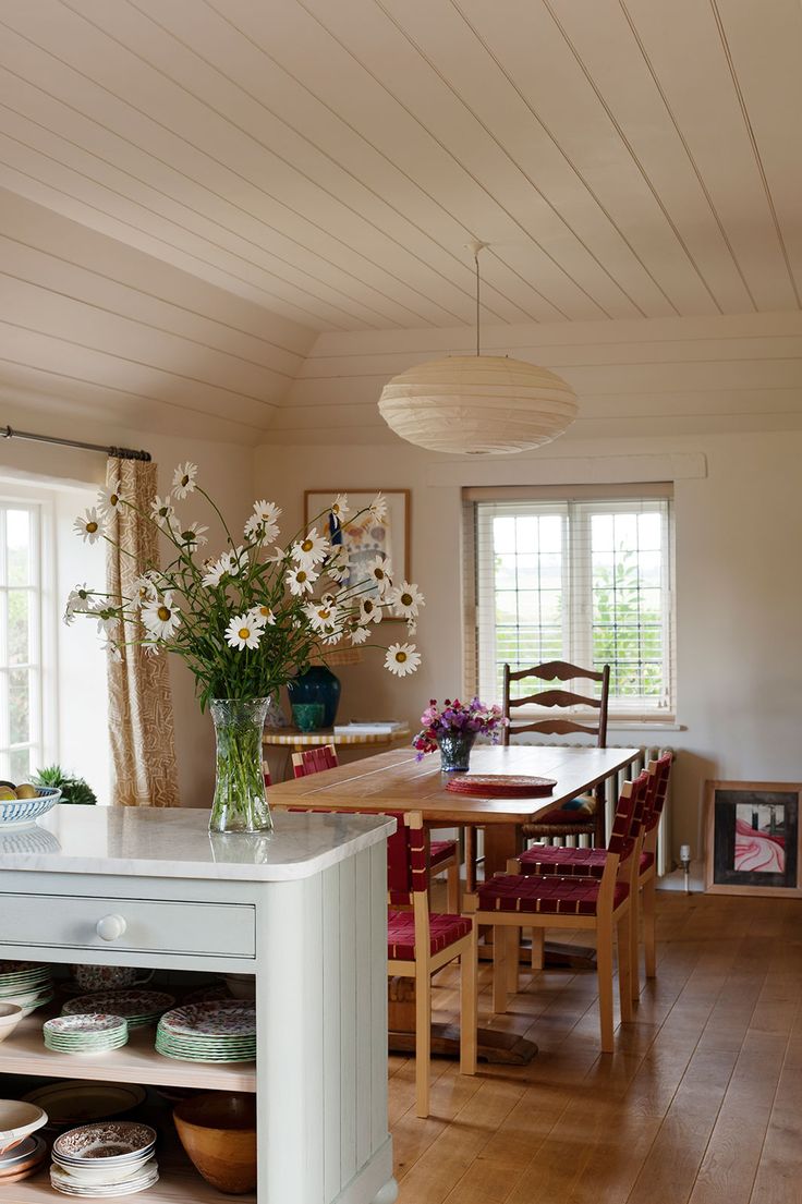 a kitchen with wooden floors and white walls has flowers in a vase on the island