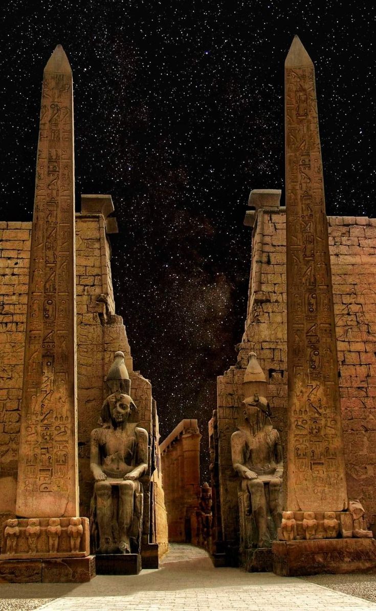 two large statues sitting next to each other in front of a night sky filled with stars