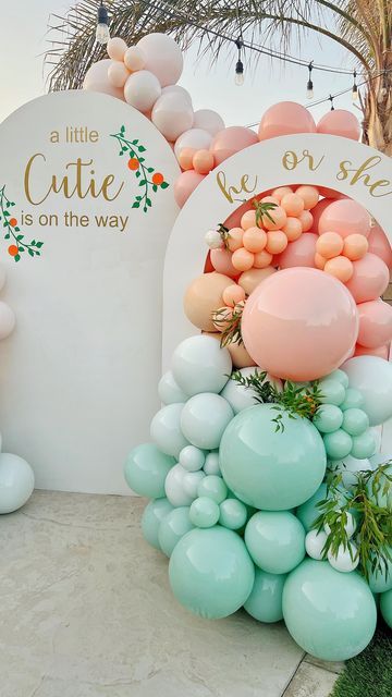 balloons and greenery decorate the entrance to a baby shower